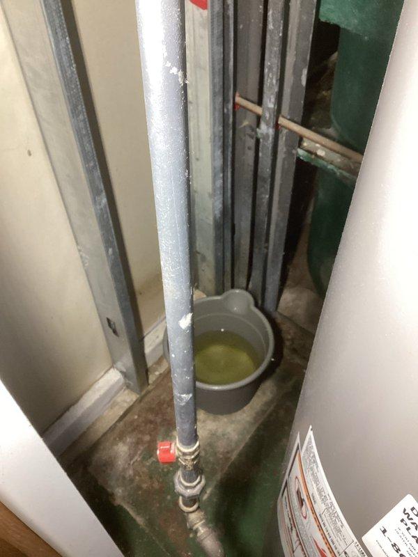 Inspected water heater flue system and identified significant corrosion and deterioration at the vertical vent pipe connection, resulting in water leakage from the flue. Documented the condition with photos showing the corroded metal joint and collected condensate. Submitted parts order for replacement tee fitting to restore proper venting integrity and prevent further moisture infiltration.