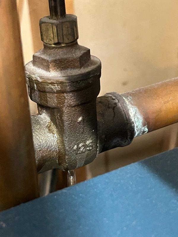 Responded to service call for a leaking shut-off valve on a 10+ year old boiler system. Inspection revealed significant corrosion and mineral deposits on a 1-inch copper pipe valve that had begun leaking. Performed complete valve replacement, including system drainage and proper refill to restore proper operation.