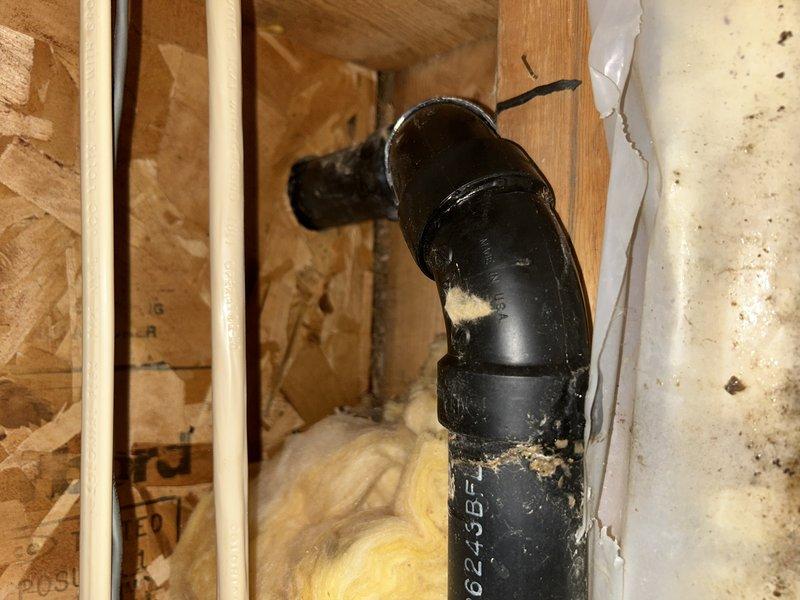 Responded to call regarding kitchen sink drain leaking into basement ceiling. Upon inspection, located source of leak in kitchen drain line. Removed section of wall to access the affected area, replaced damaged pipe section with new PVC fittings and secured with PROFLEX clamp. Observed water damage and possible mold on surrounding wooden framing.