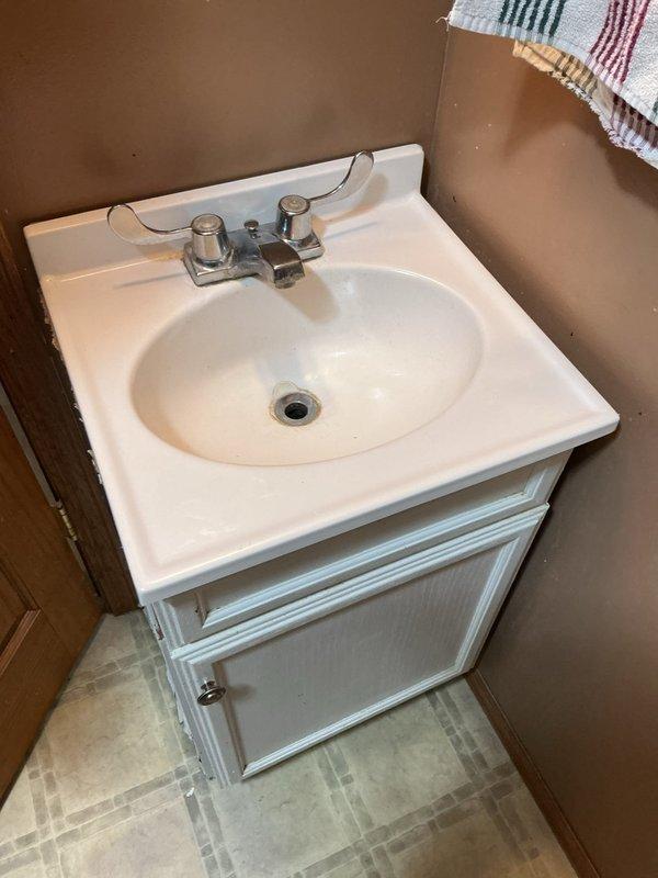 Inspected bathroom sink with reported cold water leak. Found dripping supply line connection at shut-off valve. Advised customer regarding options to replace stop valve and supply line immediately or replace entire vanity due to water damage and cabinet deterioration. Customer elected to procure new vanity and faucet themselves, with installation to be scheduled at a later date.