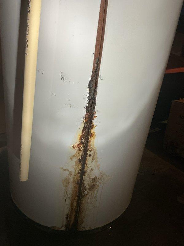 Replaced 67-gallon electric water heater that had catastrophically failed after 19+ years of service. Original unit exhibited significant corrosion with vertical split along tank seam causing active leakage. Installed new 50-gallon electric water heater and established customer on preventative maintenance program.