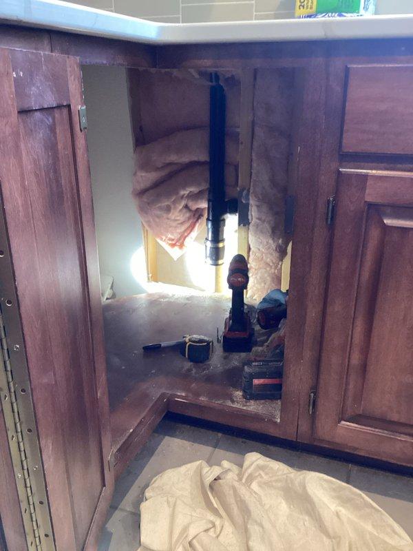 Completed kitchen drain rerouting project which involved cutting a 2" drain in basement, removing sheetrock behind lazy susan cabinet, and installing new kitchen drain line through cabinet floor. Successfully tied vent into basement drain and installed an Air Admittance Valve (AAV) for proper venting. Connected kitchen sink drains as needed to complete the plumbing system.