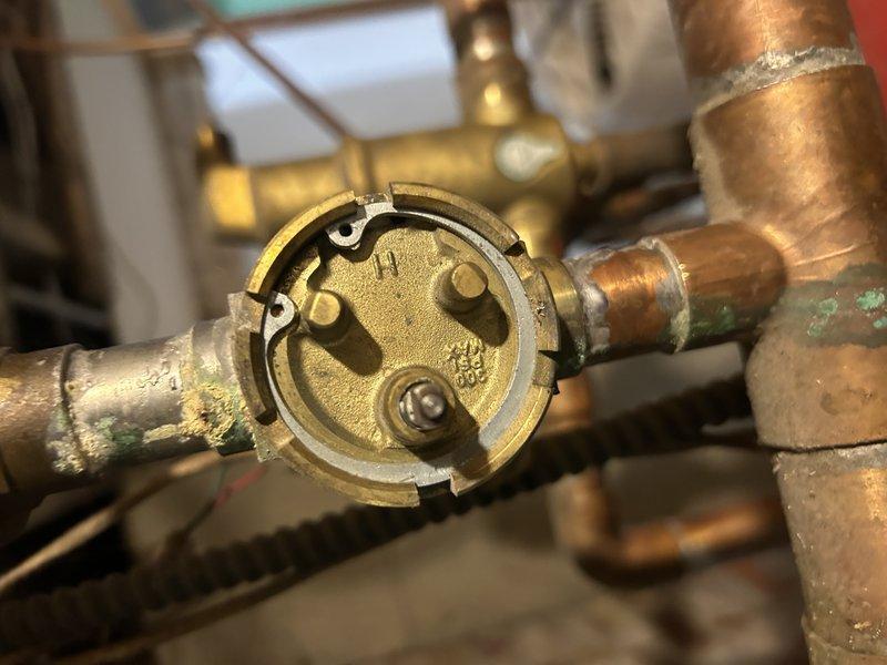 Performed diagnostic inspection on zone valve system and identified need for power head replacement. Upon arrival, discovered incorrect replacement part was provided. Documented existing valve configuration with photos showing copper piping assembly and internal components of the current zone valve head. Service to be completed on return visit with proper replacement parts sourced from alternate location.