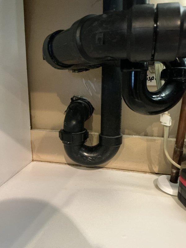 Identified and resolved kitchen sewer odor issue by discovering a dry P-trap. Cut off the deteriorated P-trap assembly and installed new PVC drain configuration with proper water seal to eliminate sewer gas infiltration.