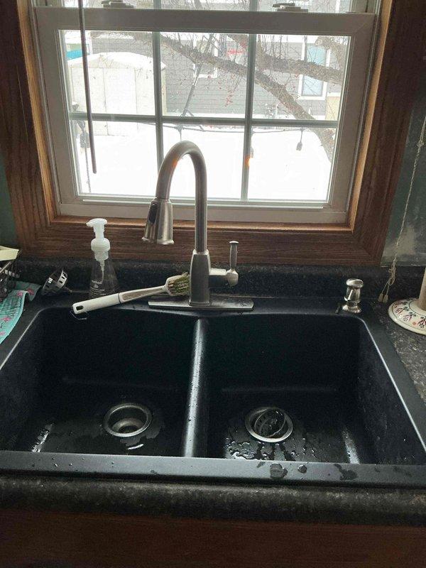 Responded to service call for a clogged kitchen sink. Upon inspection of the double-basin black sink, water drainage issues were evident. Successfully cleared the blockage using drain snake technique on the kitchen sink drain line. Confirmed proper drainage functionality after service completion.
