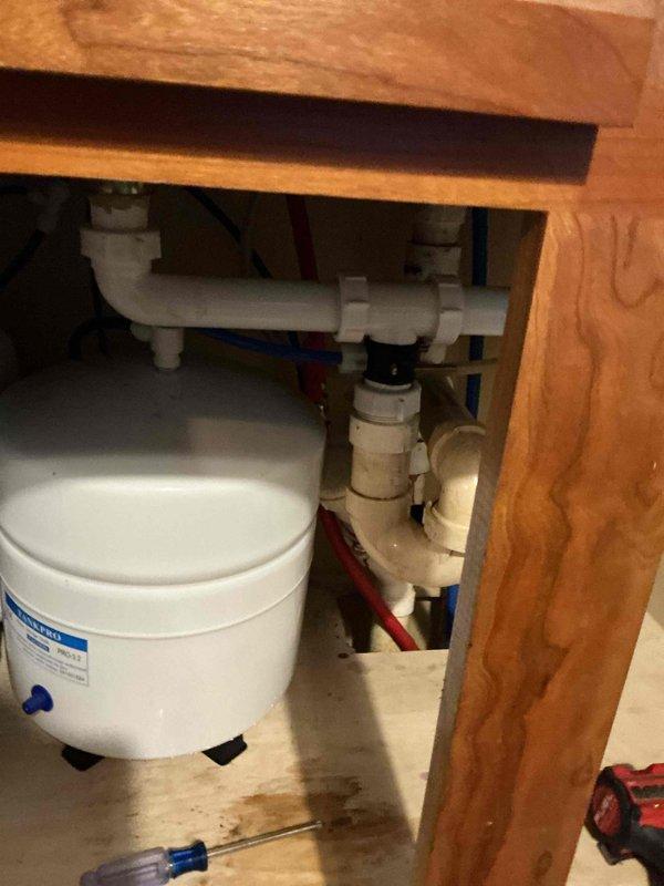 Responded to water leak complaint from RO system. Identified water leaking from air gap hole in faucet, indicating a clogged drain line. Located and removed blockage in the blue tube connecting to the drain pipe, resolving the issue and preventing further counter water damage.