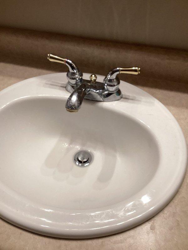 Successfully installed customer-supplied lavatory faucet in bathroom sink. Removed old two-handle chrome fixture showing signs of tarnishing and water spots, and properly installed new fixture with clean connections. Verified proper operation with no leaks after installation.