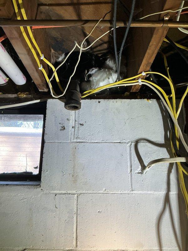 Repaired broken drain pipe in basement that connected to kitchen sink. Identified failed coupler which broke during customer's attempt to clear a clog. Removed damaged section and re-piped portion of the drainage system, replacing the corroded metal fitting with new PVC components to restore proper waste water flow.