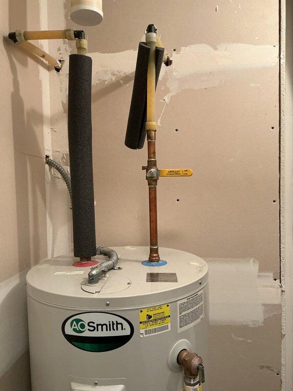 Diagnosed 20-year-old A.O. Smith 50-gallon electric water heater with active leak from tank bottom, evidenced by significant rust formation at base. Determined unit had reached end of serviceable life due to tank failure. Removed failed unit and installed new water heater with proper connections to existing plumbing system.