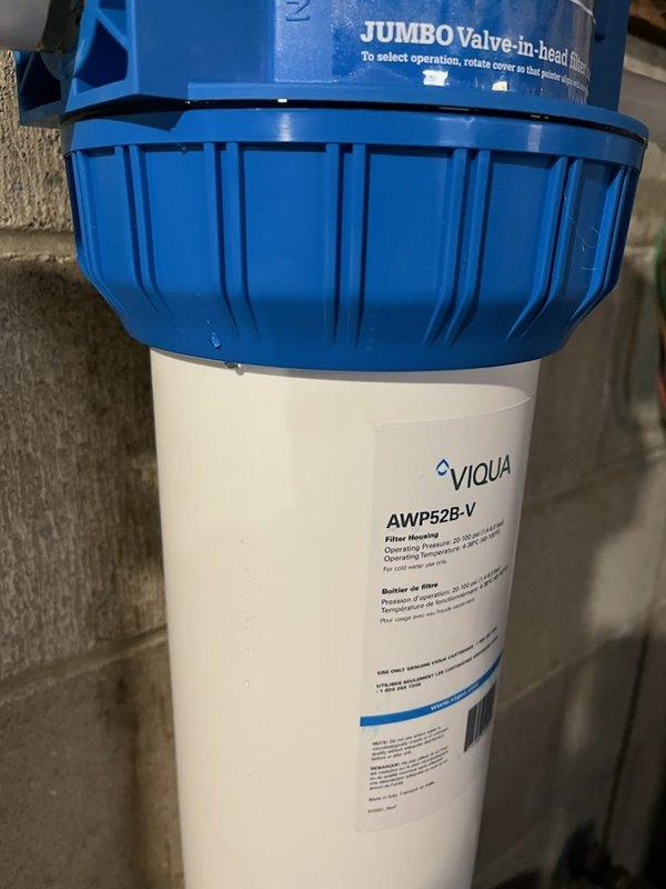 Diagnosed and repaired leak in 20-inch whole house water filter system (VIQUA AWP52B-V). Determined gray Teflon pipe dope used on gasket-to-housing seal was incompatible and causing failure. Removed all existing pipe dope and properly resealed with appropriate silicone-based product to resolve the leak issue.