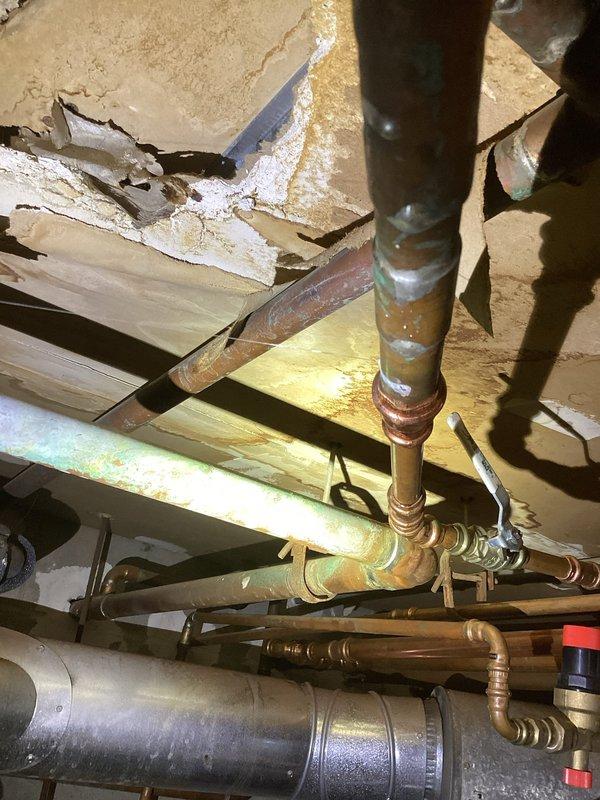 Responded to emergency service call for 18-unit apartment building with no heat. Found boiler actively leaking from cast plates with extensive water damage to surrounding ceiling and structure. Inspection revealed burned wiring inside the unit and catastrophic failure of the system. Documented damage with photos and arranged for service advisor to provide quote for complete boiler replacement due to irreparable condition.