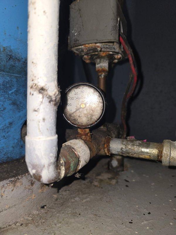 Diagnosed water pressure system failure with pressure tank operating at critically low 1-5 PSI causing no water pressure in home. Installed new pressure switch to restore system functionality after confirming severe corrosion at pipe junctions and pressure gauge connections. System now operating within normal parameters.