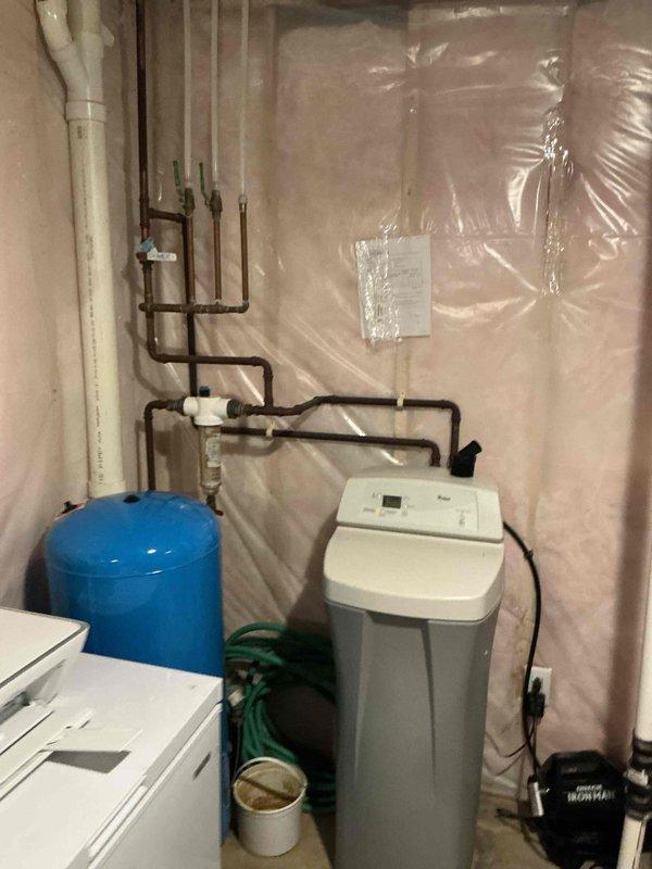 Inspected 12-year-old water heater and water softener system per customer concern about egg odor in laundry room. Determined both units are functioning properly, with odor likely caused by washer discharge pipe being inserted too far into standpipe, causing P-trap siphoning. Repositioned discharge hose to proper depth and advised customer on cleaning tub overflow to address separate odor issue in that location.