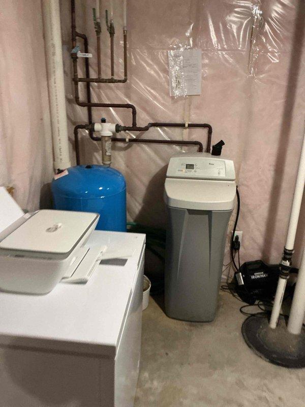 Inspected 12-year-old water heater and water softener system per customer concern about egg odor in laundry room. Determined both units are functioning properly, with odor likely caused by washer discharge pipe being inserted too far into standpipe, causing P-trap siphoning. Repositioned discharge hose to proper depth and advised customer on cleaning tub overflow to address separate odor issue in that location.