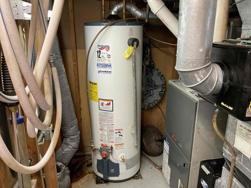 Diagnosed 15-year-old Richmond 40-gallon natural gas water heater with active leak from tank top. Unit (2004 model) determined to be non-repairable due to age and tank deterioration. Provided options for replacement including customer-supplied heater option. Existing installation includes copper supply lines, atmospheric venting, and standard gas connection.