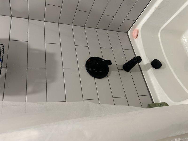 Completed installation of customer-supplied shower valve as previously assessed by Charlie. Removed existing valve and installed new replacement unit in tiled bathroom area. Work involved accessing plumbing behind framed wall structure.