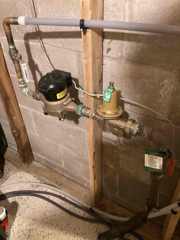 Installed a new adjustable water pressure regulator (up to 1") to replace failing unit. Initial testing showed pressure readings of approximately 50-60 PSI on the Bluefin gauge. The regulator was properly mounted to the concrete block wall with copper and PVC connections, ensuring optimal water pressure throughout the property and protecting pipes and fixtures from excessive pressure damage.