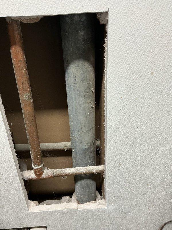 Diagnosed and resolved clogged bathroom sink drain line connected to laundry tub sink. Identified blockage in galvanized pipe within wall, cut access panel, and performed line cleaning to restore proper drainage function.