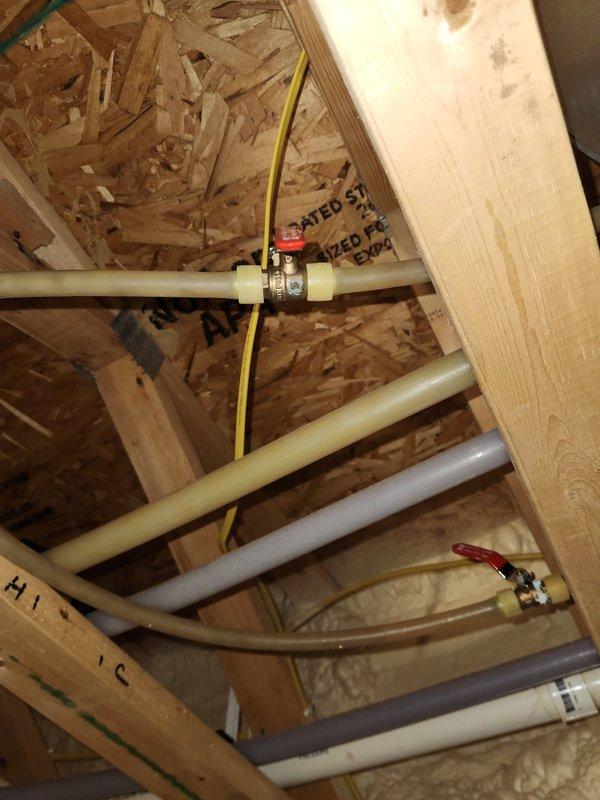 Replaced two corroded brass ball valves exhibiting pinhole leaks in the plumbing system. Leakage likely caused by high pH levels in water or excessive water velocity through PEX piping from recirculation pump. New valves installed within wooden framed structure with proper connections to existing PVC piping.