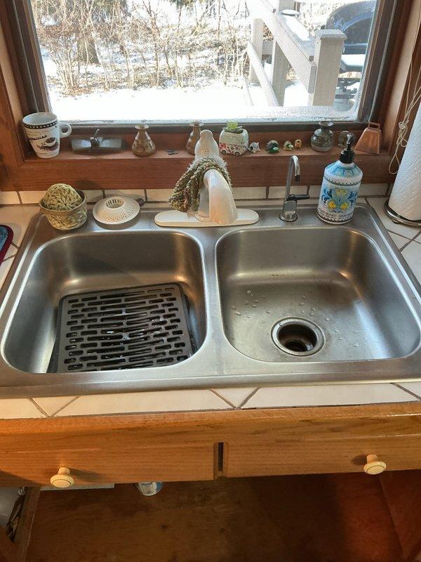 Responded to service call for leak beneath kitchen sink. Upon inspection, discovered a small pinhole in the chrome P-trap due to corrosion, causing a minor drip. Discussed repair options with customer, including replacement of the affected section of piping, while noting customer's interest in potentially installing a new faucet and sink in the future.