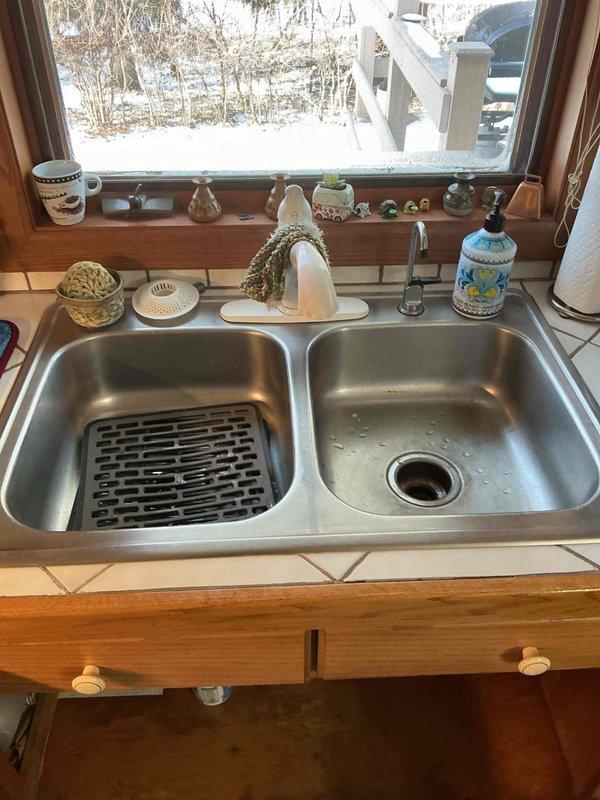 Responded to service call for leak beneath kitchen sink. Upon inspection, discovered a small pinhole in the chrome P-trap due to corrosion, causing a minor drip. Discussed repair options with customer, including replacement of the affected section of piping, while noting customer's interest in potentially installing a new faucet and sink in the future.
