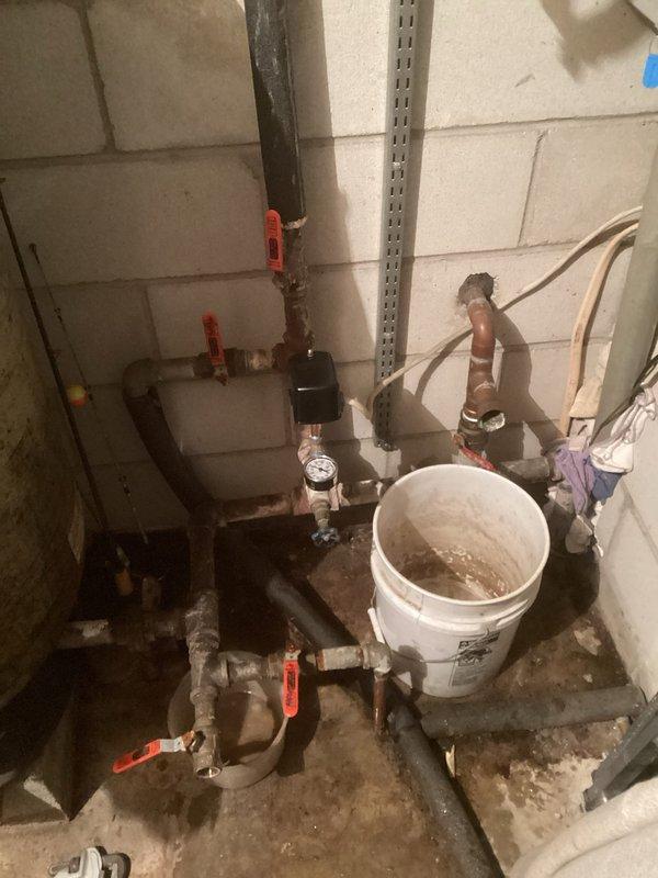 Responded to service call for no water and well system over-pressurizing house. Diagnosed issue with pressure switch and replaced it, but problem persisted. Identified need for electrical box replacement inside the house for the well system. Observed significant corrosion on pipe connections and mineral buildup around joints and valves. Noted water softener/filtration tank with substantial staining and evidence of previous leakage.