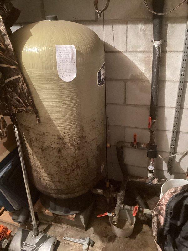 Responded to service call for no water and well system over-pressurizing house. Diagnosed issue with pressure switch and replaced it, but problem persisted. Identified need for electrical box replacement inside the house for the well system. Observed significant corrosion on pipe connections and mineral buildup around joints and valves. Noted water softener/filtration tank with substantial staining and evidence of previous leakage.