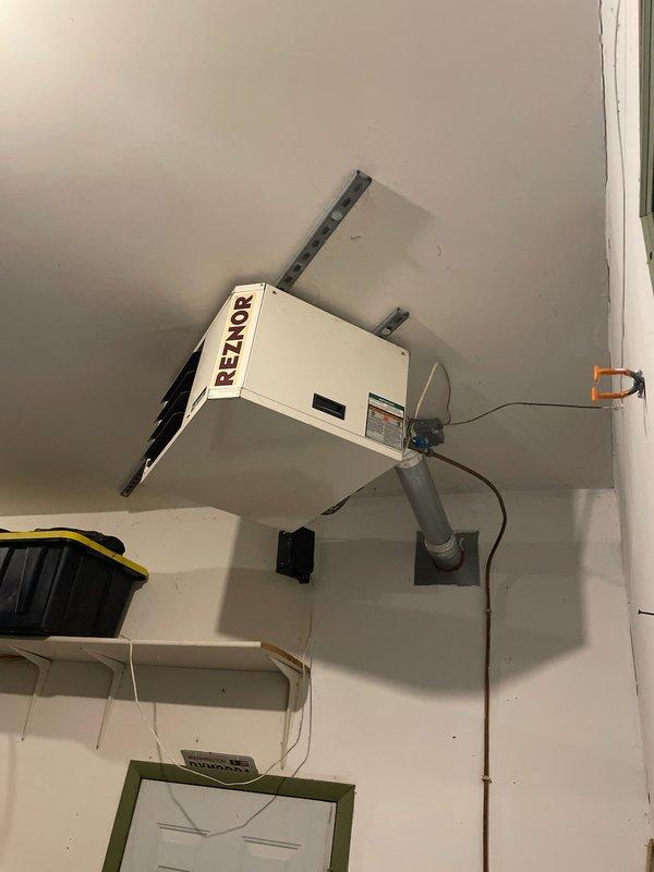 Responded to no-heat call for ceiling-mounted Reznor garage heater. Diagnosed blower motor failure due to age. Replaced motor to restore heating functionality. Unit is now operating within normal parameters.