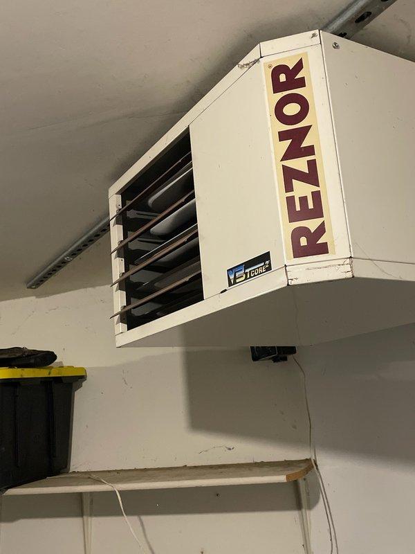 Responded to no-heat call for ceiling-mounted Reznor garage heater. Diagnosed blower motor failure due to age. Replaced motor to restore heating functionality. Unit is now operating within normal parameters.