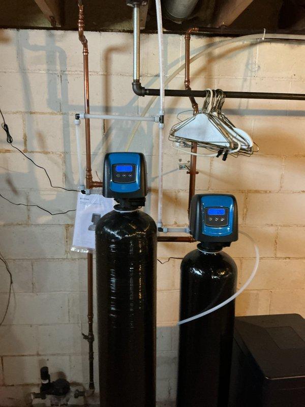 Identified and repaired a leak at the adapter connecting the water softener to the drain line. Inspection revealed the issue stemmed from the installation configuration where both water treatment tanks were connected to a single drain line using the original softener drain pipe. Properly secured connections to eliminate the intermittent leak that had persisted despite previous repair attempts.