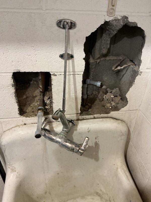 Responded to emergency burst pipe call at commercial facility. Located solder joint failure within wall, requiring controlled demolition of concrete block to access. Capped copper supply lines in mechanical room to isolate damaged mop sink faucet which had split open. Customer will need replacement mop sink faucet ordered and installed.
