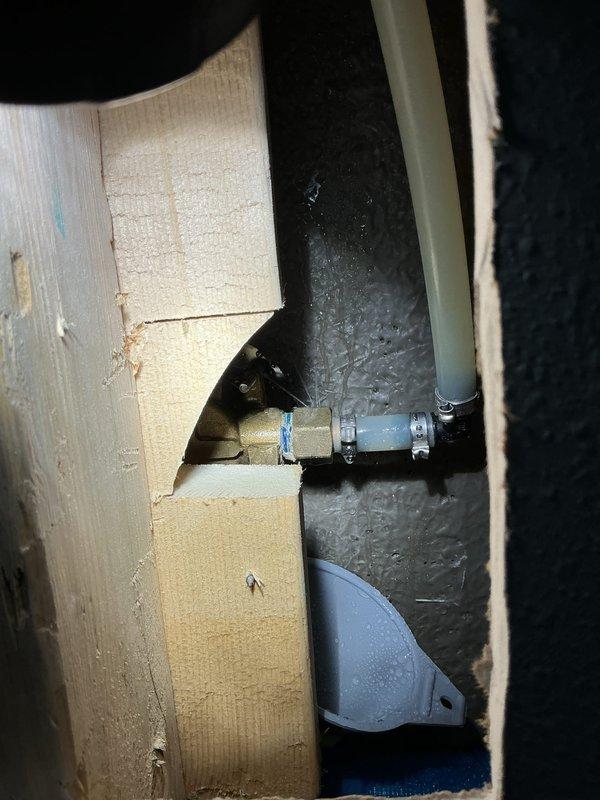 Repaired water leak at tub valve body by identifying a pin hole leak in the brass fitting. Accessed plumbing infrastructure through wall cutout, installed crimp fittings to successfully resolve the leak issue and restore proper function to the shower/tub water connection.