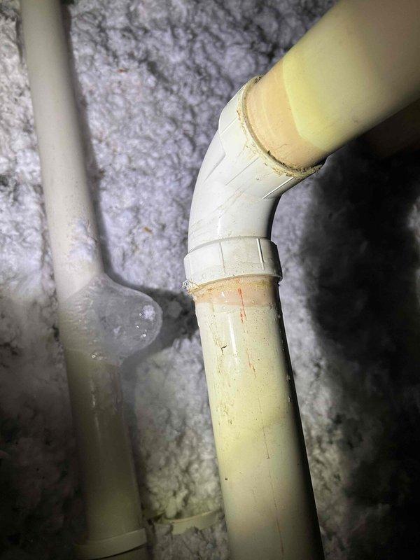 Responded to no-heat call for 4-year-old system. Diagnosed exhaust pipe blockage on roof that had frozen over, requiring removal of T-fitting to clear obstruction. Upon roof inspection, discovered excessive pipe movement which led to attic investigation where a disconnected exhaust elbow was found venting combustion gases into attic space. Repaired and secured the disconnected elbow joint with appropriate adhesive to restore safe operation. Noted lack of insulation on all attic exhaust piping, which likely contributed to condensation freezing. Recommended insulation installation for all exhaust runs to prevent future blockages.