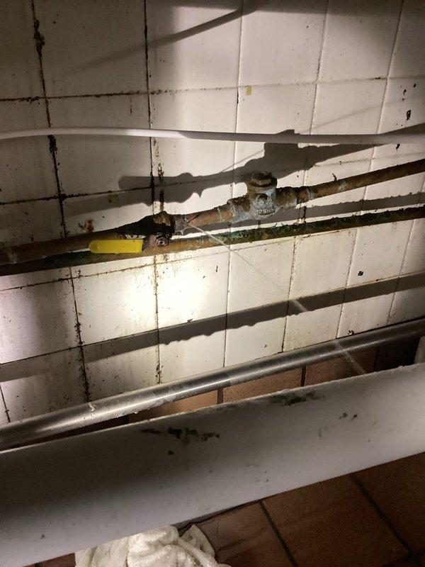 Responded to emergency call for a leaking pipe under sink in restaurant. Identified pinhole leak in corroded copper pipe with significant water damage to surrounding wall tiles. Replaced faulty component with new ball valve, restoring proper water flow before business hours.