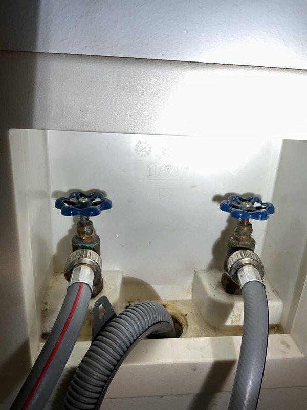 Responded to service call for leaking washer hookup valves. Inspected the recessed utility box containing hot/cold water valves and found loose packing on the hot water valve causing the leak. Tightened the packing to resolve the issue and provided customer with estimate for future toilet replacement work.