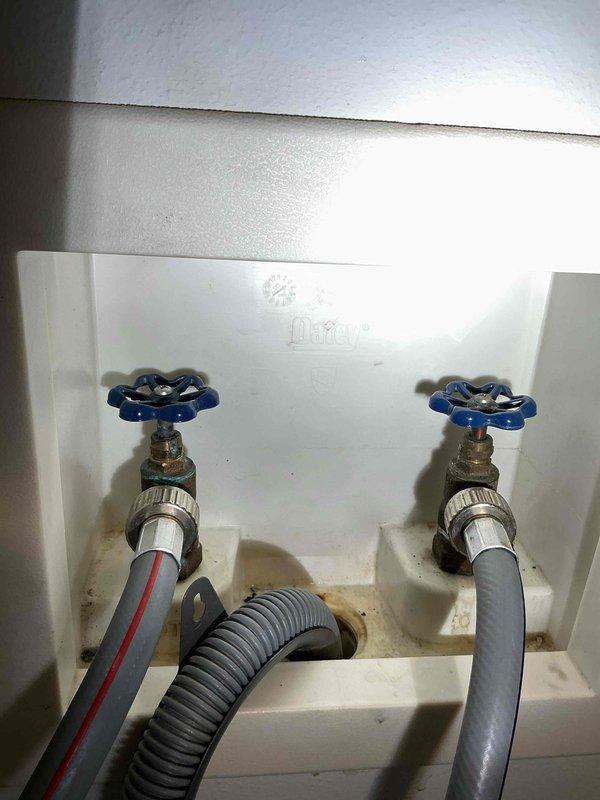Responded to service call for leaking washer hookup valves. Inspected the recessed utility box containing hot/cold water valves and found loose packing on the hot water valve causing the leak. Tightened the packing to resolve the issue and provided customer with estimate for future toilet replacement work.