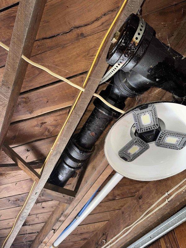 Inspected property for reported plumbing issues and identified multiple problems in the drainage system. Found two toilets backing up due to deteriorated cast iron drain piping that leaks during toilet usage. Exposed and examined the problematic plumbing infrastructure in the ceiling/wall area. Advised homeowner that professional drain cleaning services are required before toilet reinstallation can proceed, and provided estimates for resetting toilets once drain cleaning is completed.