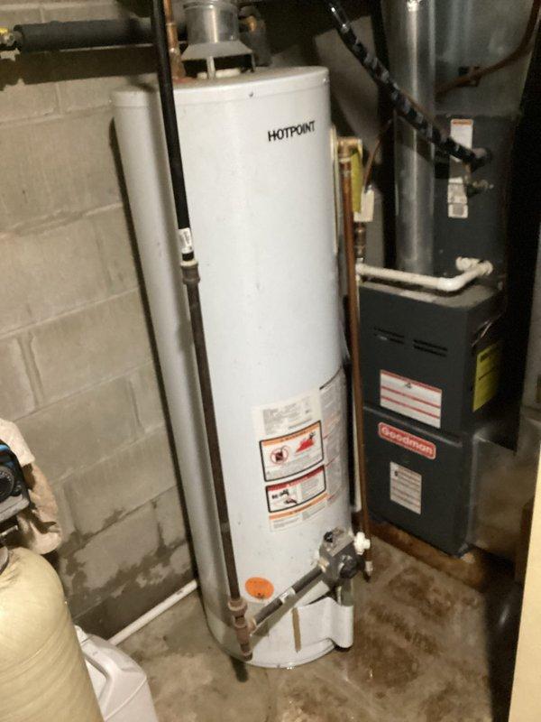 Diagnosed Hotpoint water heater leaking from bottom in utility room, identified as an internal tank leak. Unit is approximately 10+ years old natural gas model. Recommended complete water heater replacement as repair not feasible for this type of failure.