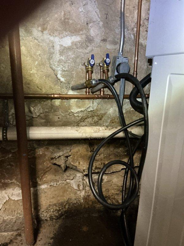 Responded to emergency call for water leak at washing machine connection point in basement. Diagnosed frozen and broken supply lines causing water spray from 12-4 valve. Replaced washing machine supply lines and verified proper function with no further leakage.