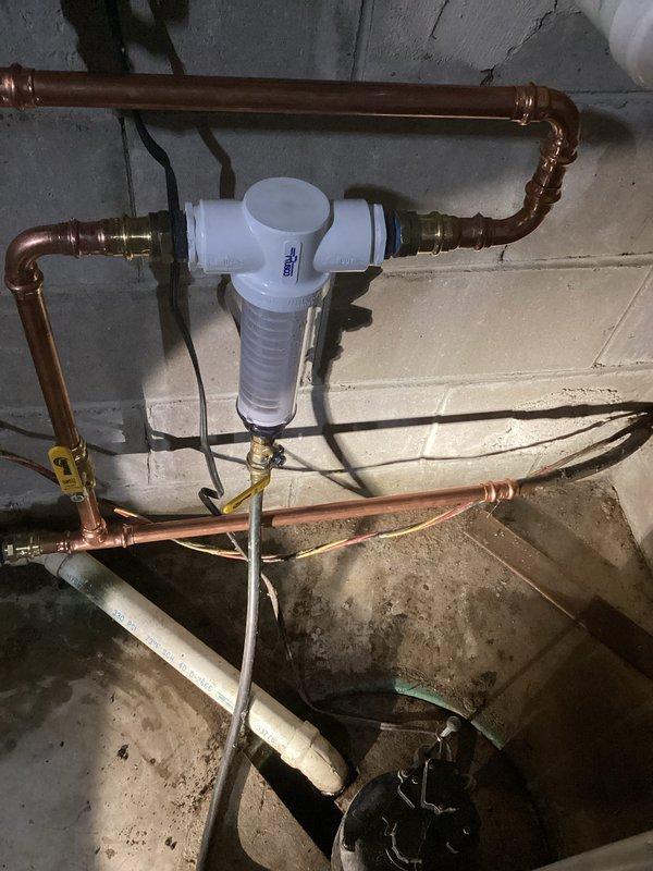 Installed a Rusco Spin Down Whole House Sediment 1" Inline Filter to improve water quality and protect plumbing fixtures from mineral damage. Removed old gate valve and completed all necessary pipe connections. Tested hot water lines and identified potential recirculation pump issue, as no vibration was detected when pump was plugged in, with temperature differential of approximately 10 degrees observed when recirculation line was closed.