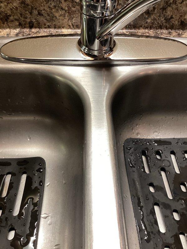 Responded to callback for recently replaced faucet that was leaking underneath. Determined leak was occurring through trim plate due to sink indentation. Applied silicone to deck plate to create proper seal and prevent further leakage.