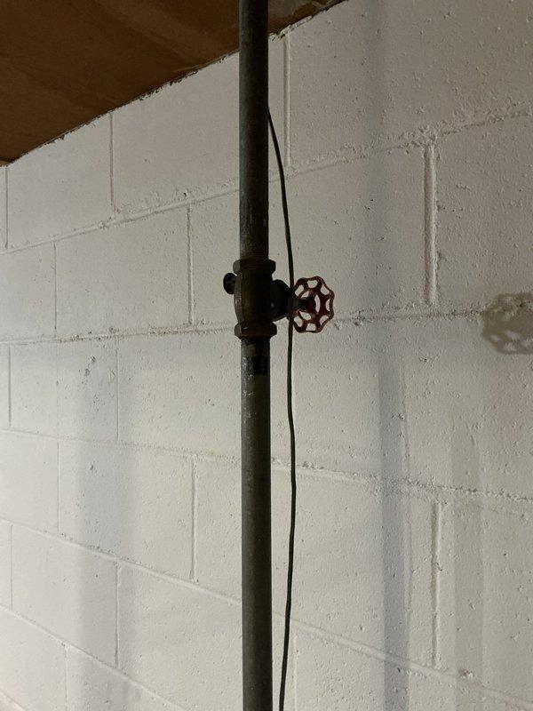 Responded to water leak in unit 12-4 originating from an old gate valve on galvanized water line after meter. Tightened the packing nut on the gate valve to stop the leak. Recommended replacement of aging water piping system to prevent future issues.