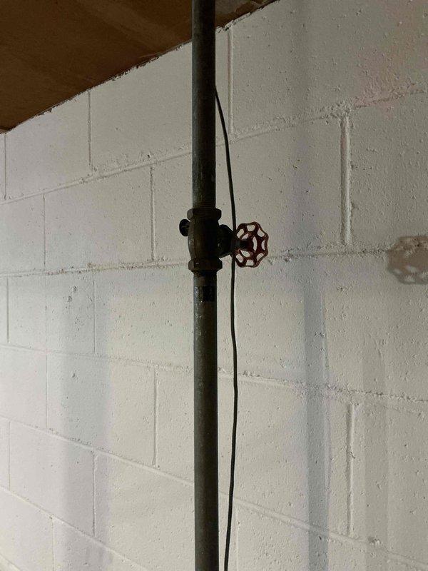 Responded to water leak in unit 12-4 originating from an old gate valve on galvanized water line after meter. Tightened the packing nut on the gate valve to stop the leak. Recommended replacement of aging water piping system to prevent future issues.