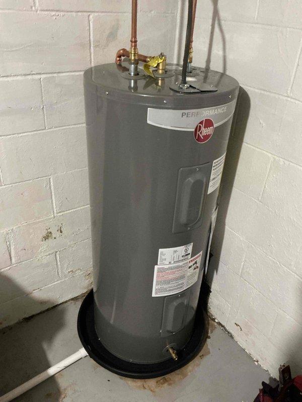 Replaced customer-supplied 40-gallon electric Rheem Performance water heater due to rust damage on the bottom of the original unit. New installation completed with all necessary plumbing connections and properly positioned on a drain pan in the utility area.