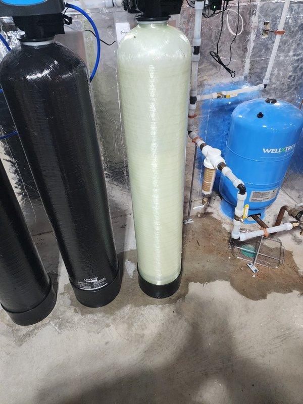 Responded to recurring water leak issue at water treatment system in basement. Diagnosed problem with faulty plastic drain adapters connected to filtration tanks that were repeatedly splitting. Replaced both drain adapters to resolve the persistent leakage problem.