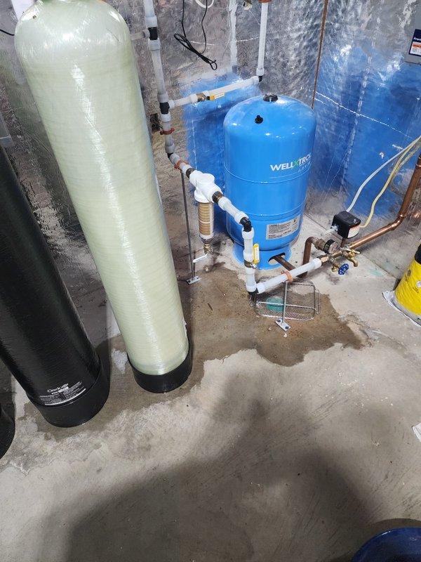 Responded to recurring water leak issue at water treatment system in basement. Diagnosed problem with faulty plastic drain adapters connected to filtration tanks that were repeatedly splitting. Replaced both drain adapters to resolve the persistent leakage problem.