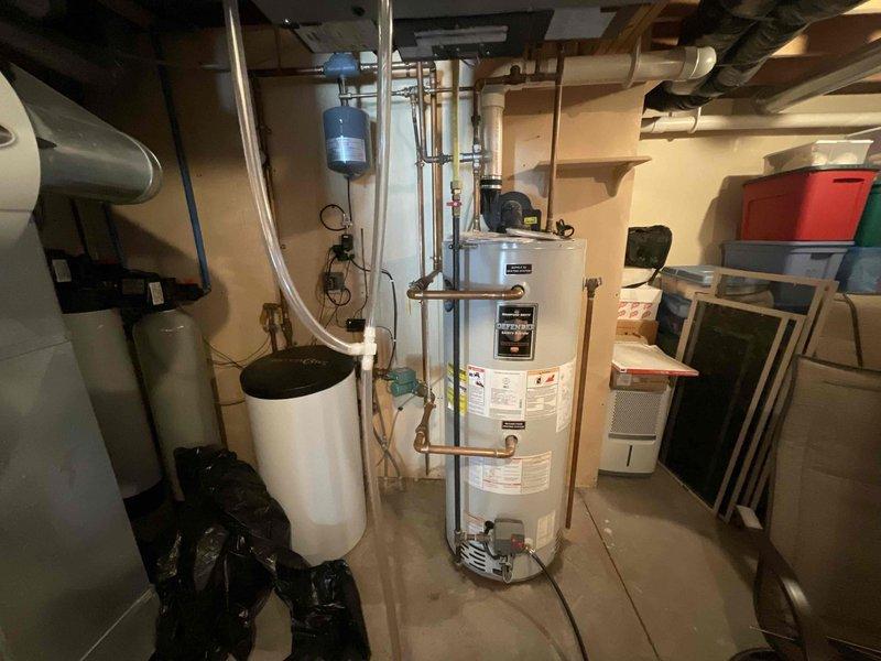 Replaced 45-gallon natural gas power-vented Bradford White water heater due to leakage. Installed new unit in basement utility room with proper connections to existing copper supply lines and PVC venting. Customer's in-floor heating system was unaffected during replacement service.