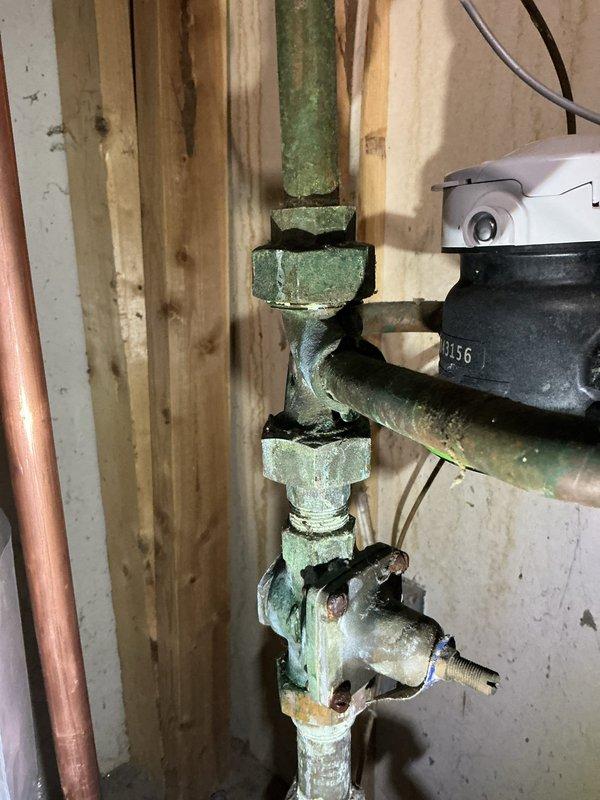 Responded to a service call for a leaking 8-12 copper pipe on water heater running from water heater to water softener. Upon inspection, identified the issue as a loose union on the main line. Tightened the union to resolve the leak, noting significant oxidation and corrosion on the existing copper piping and fittings.