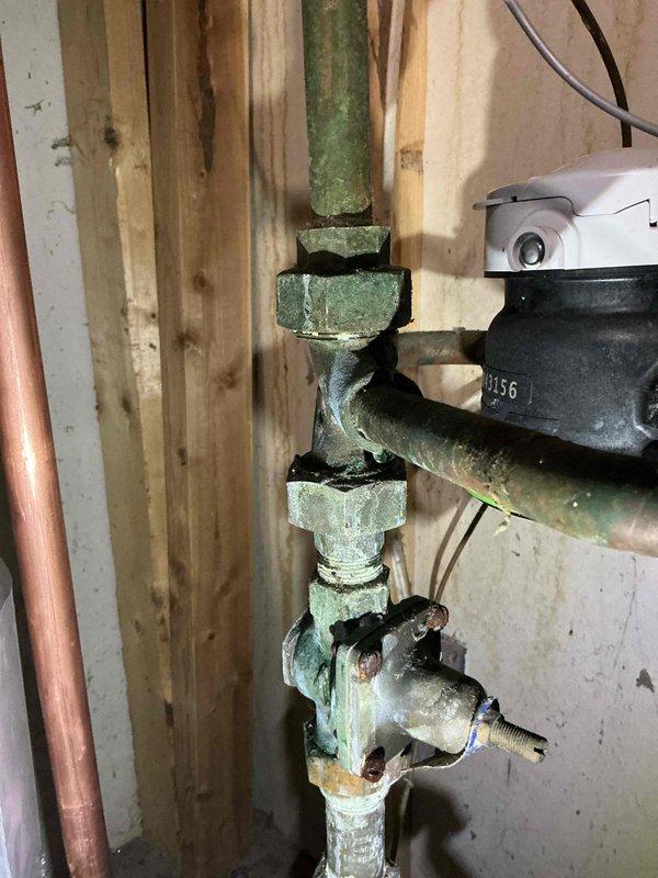 Responded to a service call for a leaking 8-12 copper pipe on water heater running from water heater to water softener. Upon inspection, identified the issue as a loose union on the main line. Tightened the union to resolve the leak, noting significant oxidation and corrosion on the existing copper piping and fittings.