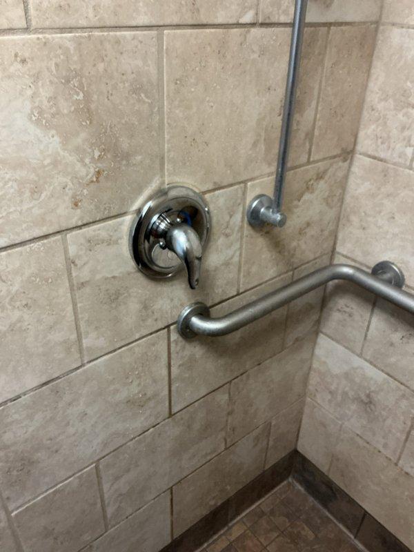 Replaced damaged shower valve handle and temperature control cartridge in fitness facility shower. Installed new trim kit and cartridge for Moen Positemp shower system. Verified proper operation and secure mounting of all components after installation.